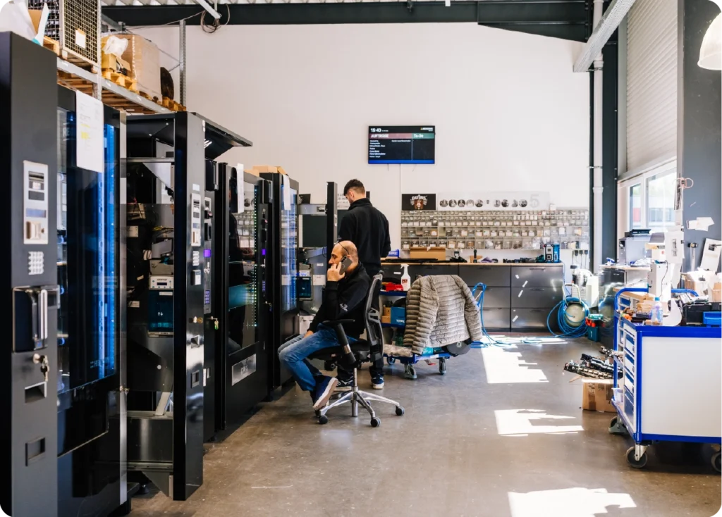 Hensing employees installing vBox devices and other equipment in vending machines while speaking with technical support.