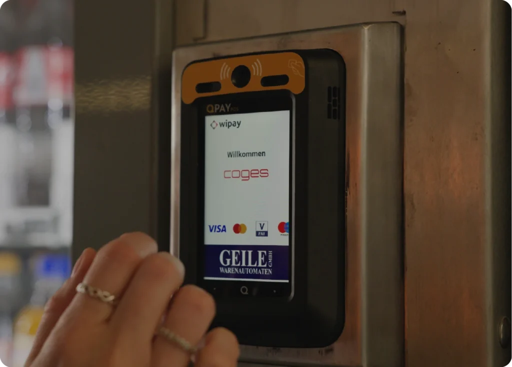 Customer paying contactlessly on a Coges Qpay terminal at a Geile Warenautomaten vending machine