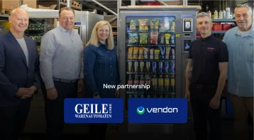 Geile Warenautomaten and Vendon teams standing beside a snack and drink vending machine, announcing their new partnership